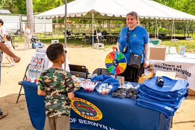 a staff member smiles at a child while manning the 2025 Town booth at Berwyn Heights Day.